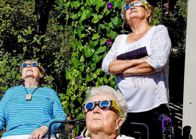 Three older women watching the solar eclipse with special protective glasses.