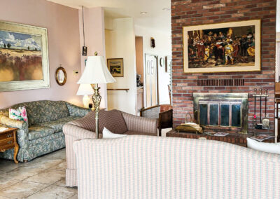 An elegant sitting room in the retirement home with cozy sofas around the fireplace and paintings decorating the walls.